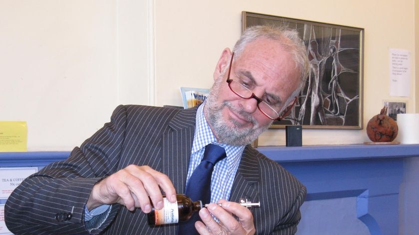 Dr Philip Nitschke with a drug and syringe, demonstrating a testing kit.