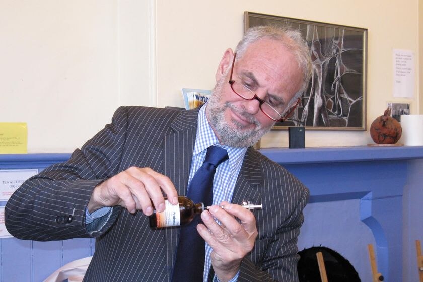 Dr Philip Nitschke with a drug and syringe, demonstrating a testing kit.