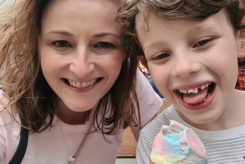 a woman lookin and smiling with a child with an ice-cream