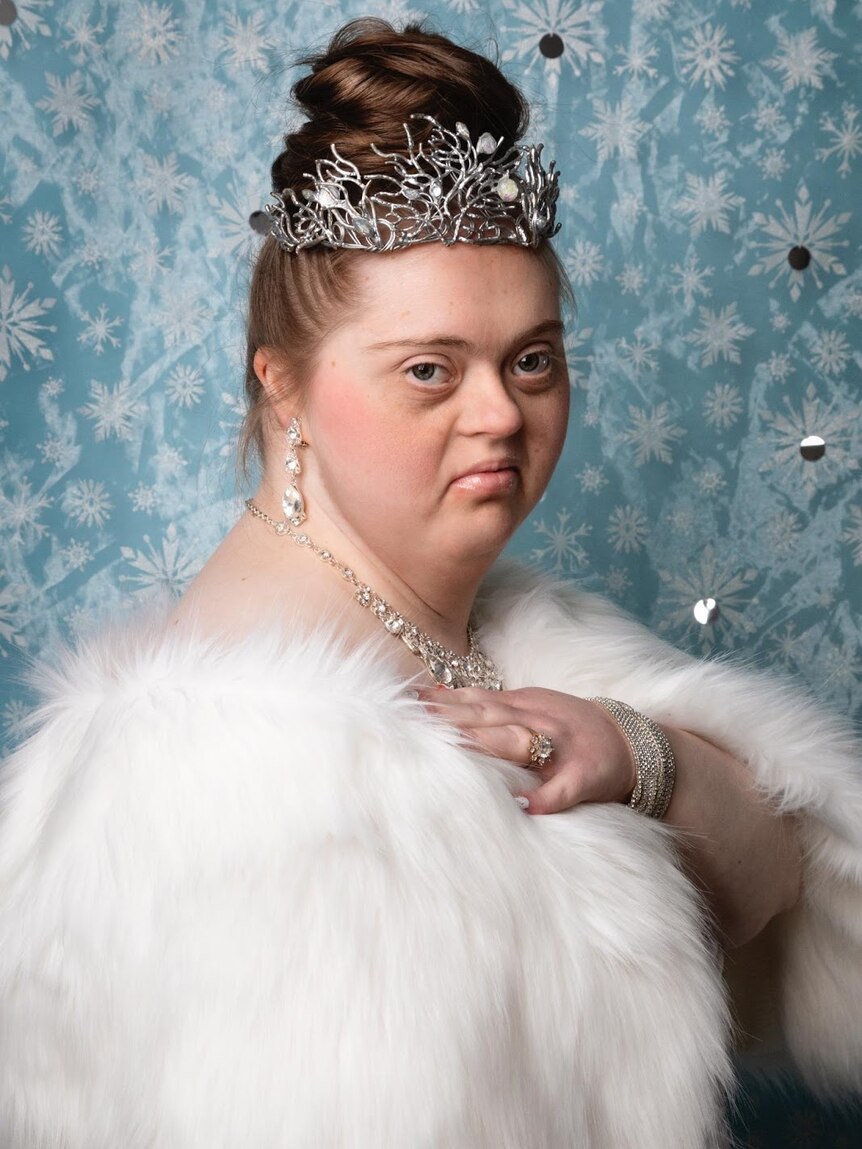 A woman with down syndrome dressed as a winter-themed princess posed gracefully
