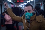 A commuter on Milan's underground railway wears a mask while listening to music with earphones.