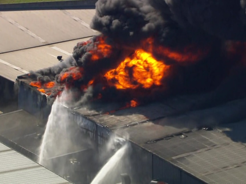 A large fire on the roof of a factory, shown from the air.