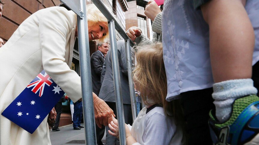 The Duchess of Cornwall smiles as she bends to meets a toddler in the crowd at Martin Place, Sydney.