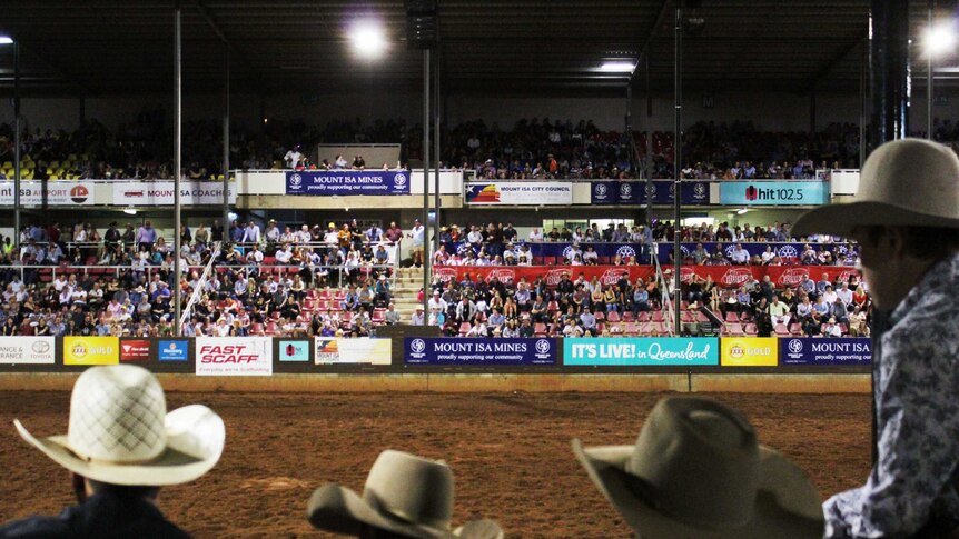 Crowd in the stands of the Mount Isa Rodeo looking on an empty field