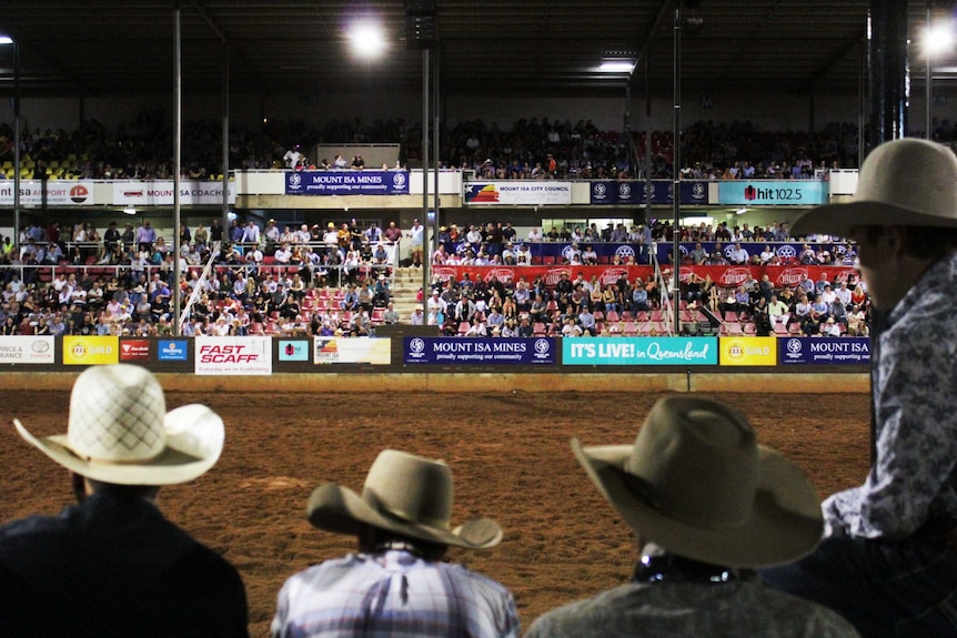 Crowd in the stands of the Mount Isa Rodeo looking on an empty field