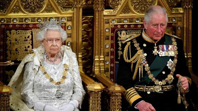 Queen Elizabeth II and the then Price of Wales, Charles sitting next to each other on golden thrones