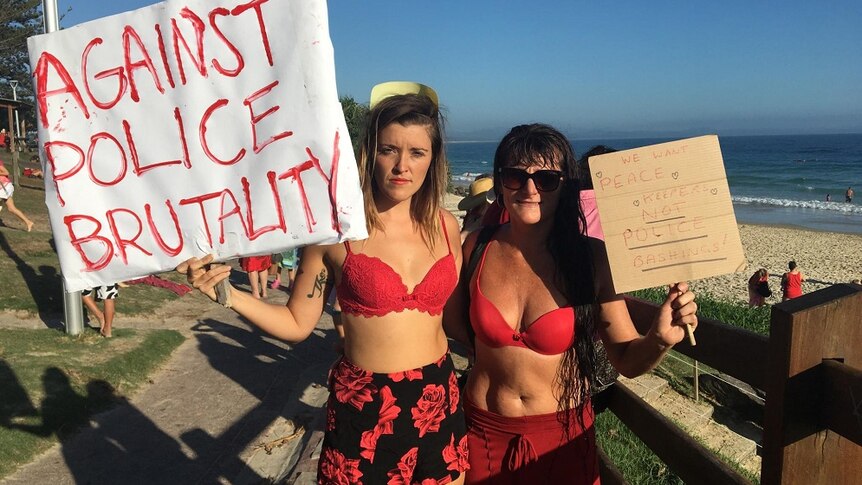 Two women holding signs protesting about what they say is police violence in Byron Bay.