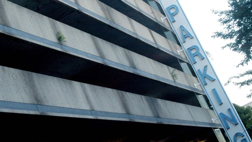 A parking sign sits on the outside of a multi-storey car park