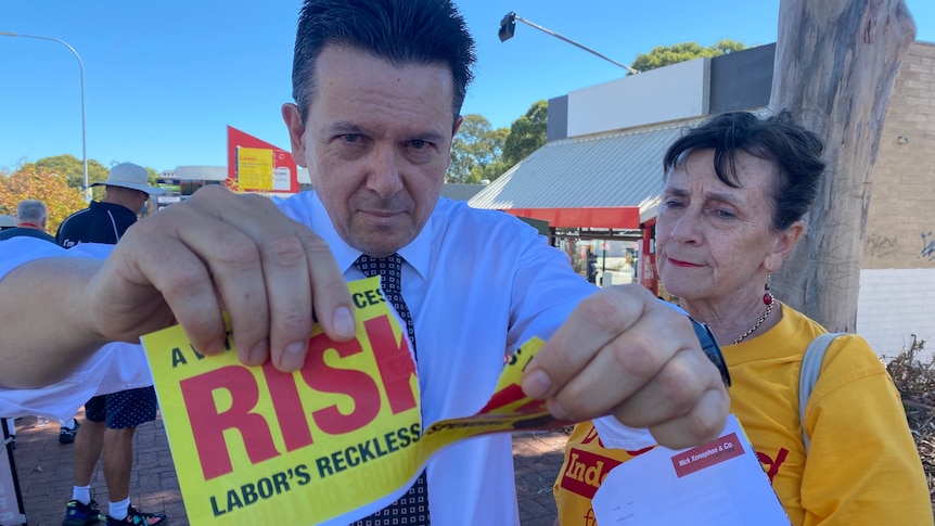 Nick Xenophon rips up a flyer as Frances Bedford looks on