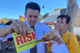 Nick Xenophon rips up a flyer as Frances Bedford looks on