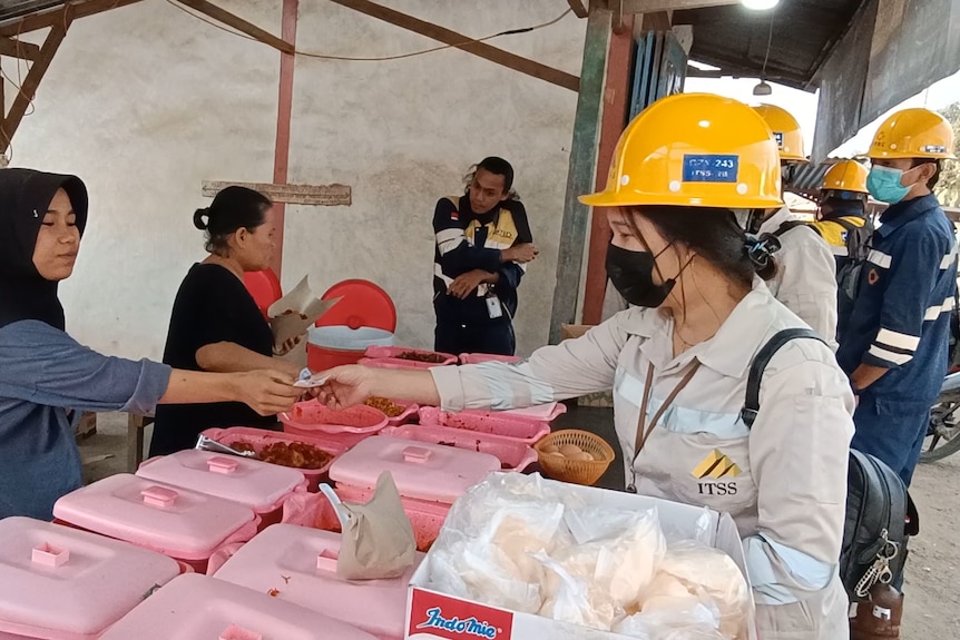 Workers wearing hard hats buy lunch.