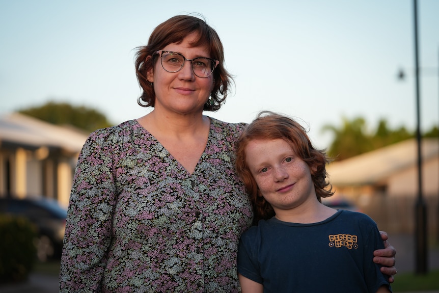 Kacey and Layne stand together smiling on a suburban street.