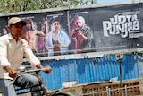 A man rides his bicycle past a poster of the movie "Udta Punjab" in Mumbai, India.