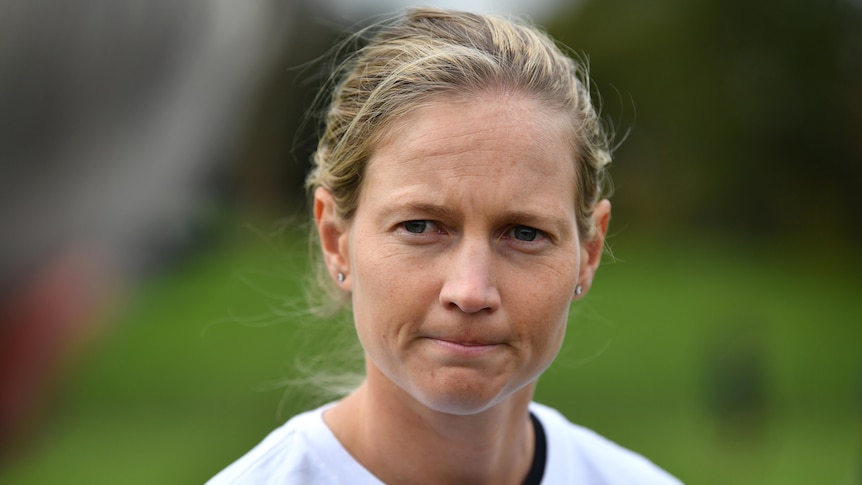 An Australian female cricket looks toward her right as she answers a question at a media conference.