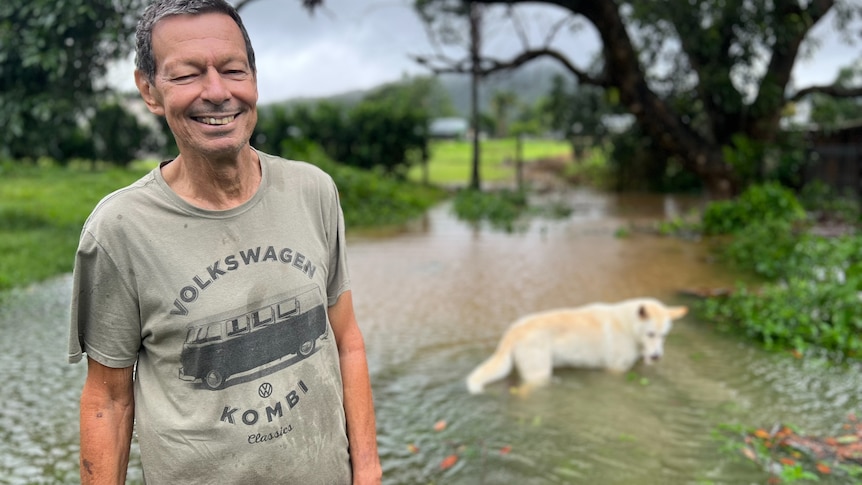 a man standing in front of flooded garden with his dog