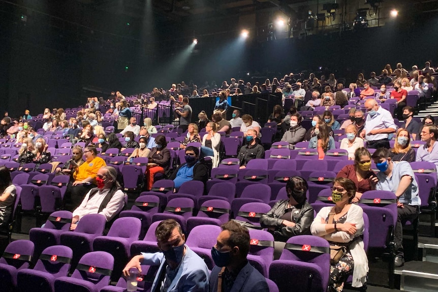 A theatre in London with people spaced out and wearing masks