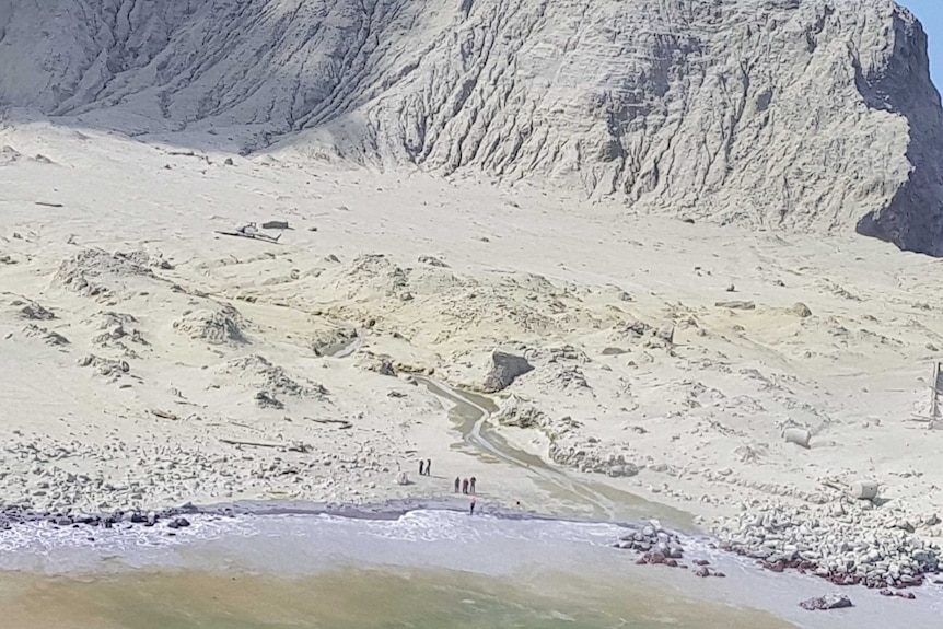 People standing on a beach are photographed from a helicopter some distance away, after a deadly island volcano eruption