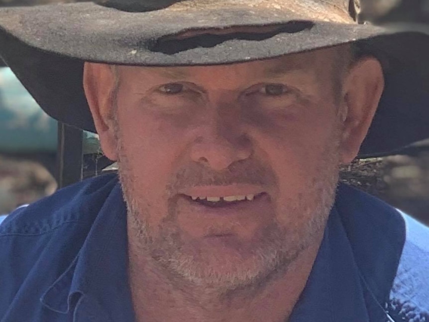 A farmer in a blue work shirt and a battered hat.