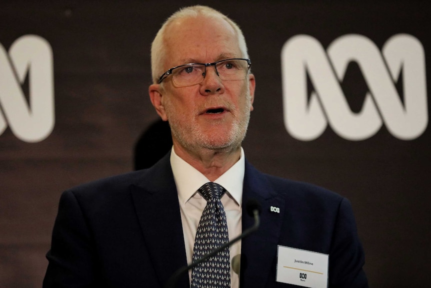 Justin Milne speaks at a podium during an evening function.