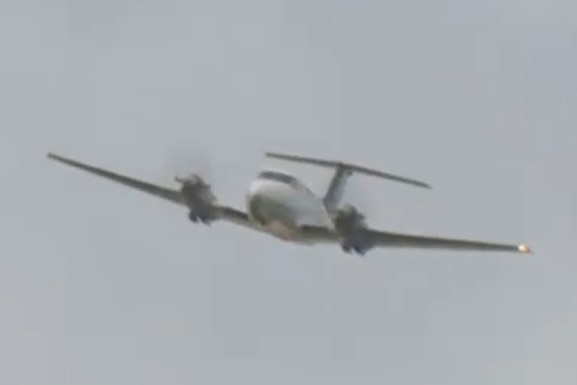 A plane flies at a low altitude with its landing gear retracted.