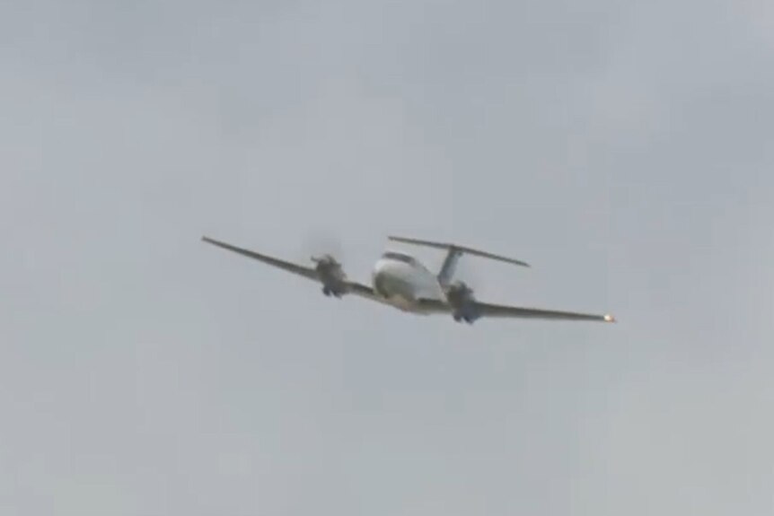 A plane flies at a low altitude with its landing gear retracted.