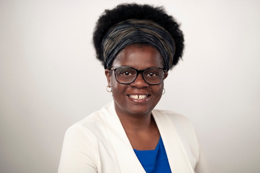 A woman wearing glasses and smiling to camera