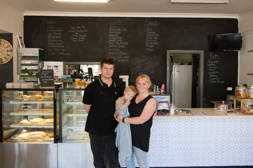 A man woman and baby in front of a counter in a Lucindale Deli.