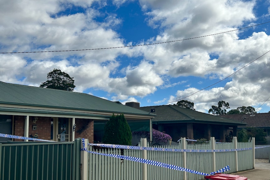 Police tape in front of a single-storey house where a woman's body was found.