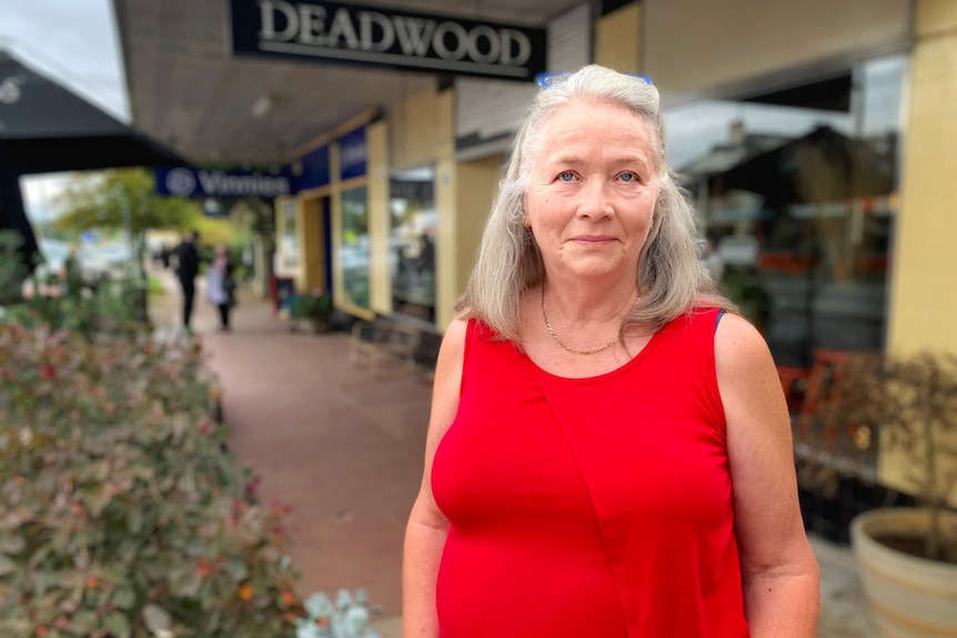 Una mujer se encuentra frente a una tienda con un gran cartel que dice DEADWOOD.