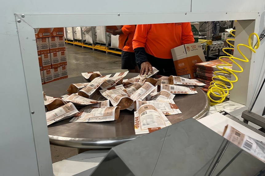 A glimpse through a window of a production line - packages are spread on a round spinning table while being boxed