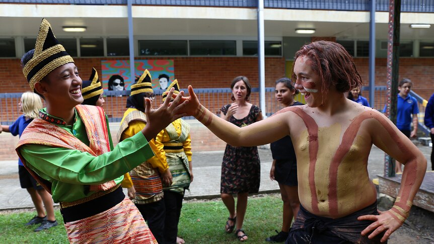 Indonesian and Aboriginal student shake hands and smile