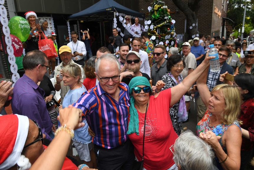 A group of people gather outside with a christmas tree and christmas decorations