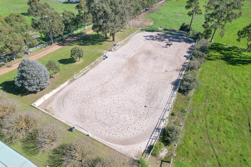 A drone shot of a horse riding arena on a farm.