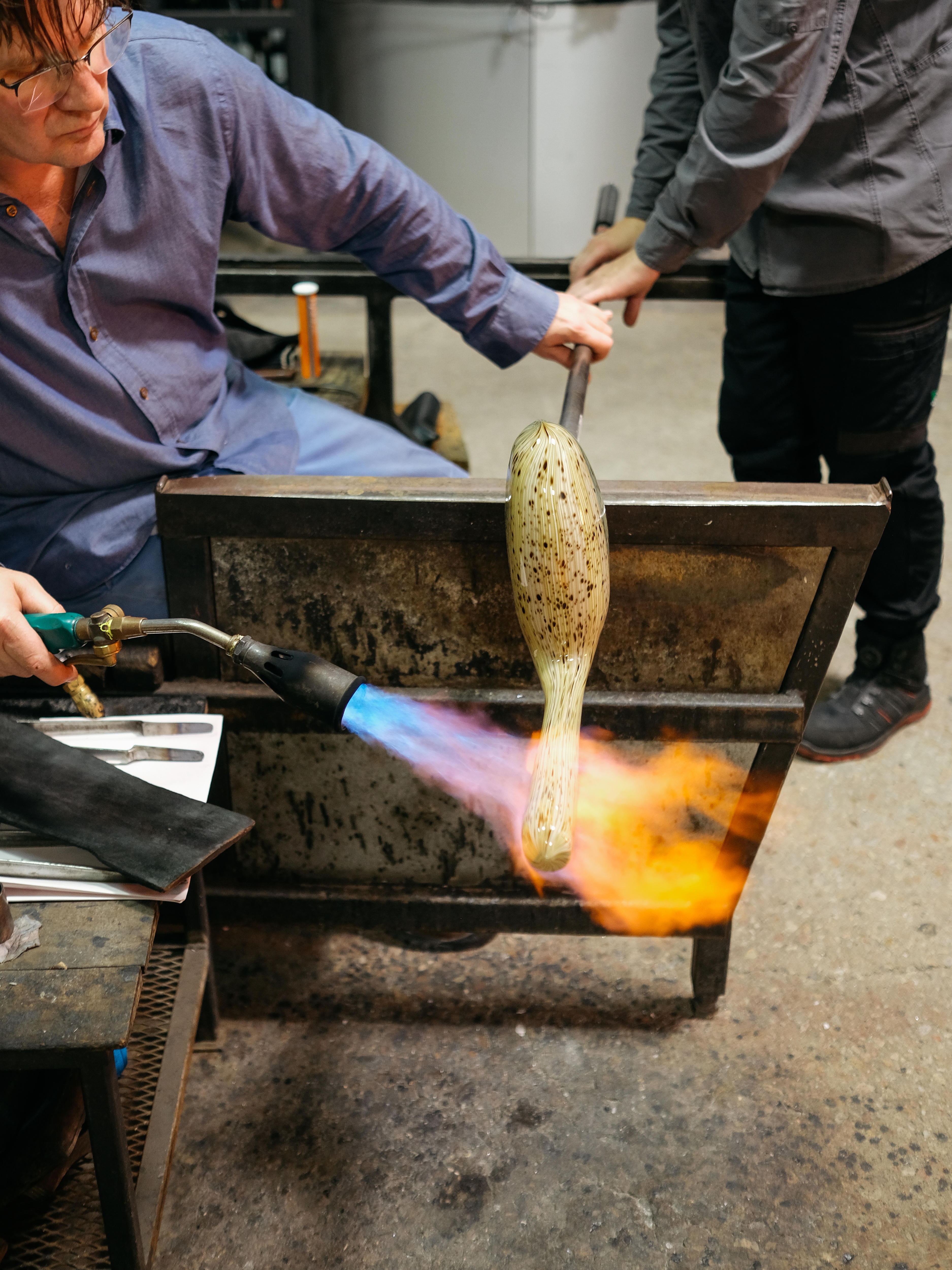 Artist Tom Moore blasts a blow torch across a sculpture he is working on in the studio