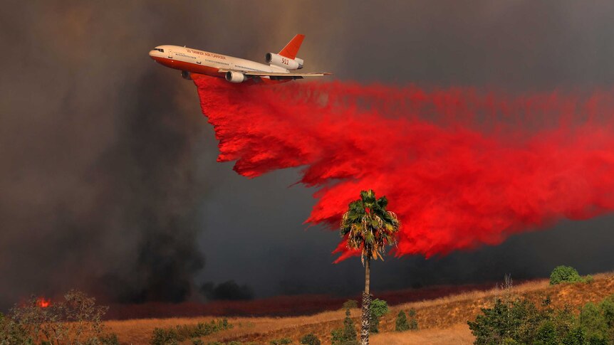 A DC-10 aircraft drops fire retardant on a wind driven wildfire in Orange County.