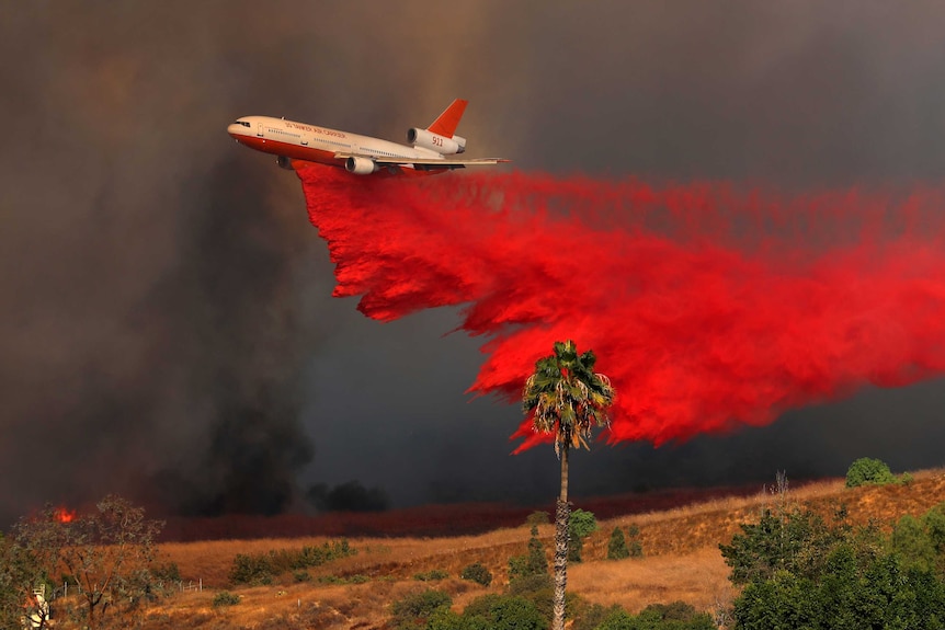 A DC-10 aircraft drops fire retardant on a wind-driven wildfire in Orange County.