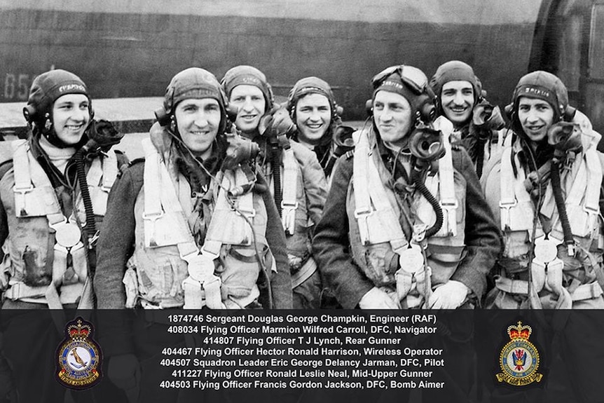 World War II flight crew wearing helmets and oxygen masks standing in front of an aeroplane.