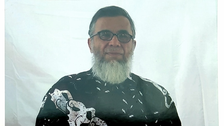 A bespectacled middle aged Indonesian man with a grey beard but no moustache wears a black and white top.