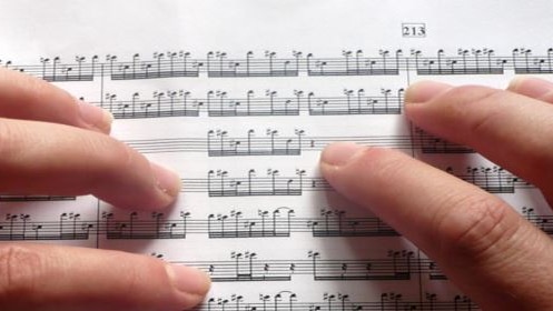 Fingers touching sheet music.