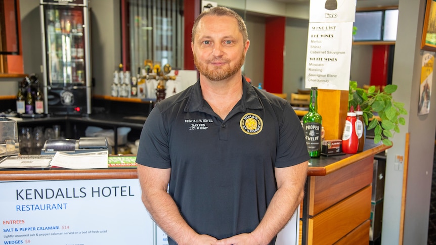 A man stands in front of a bar in a hotel