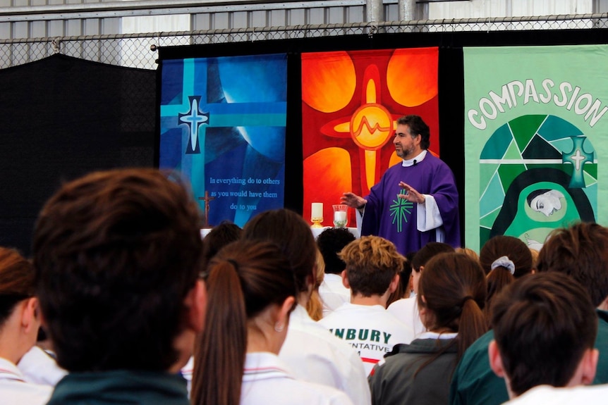 Image of a priest holding mass in front of a large audience