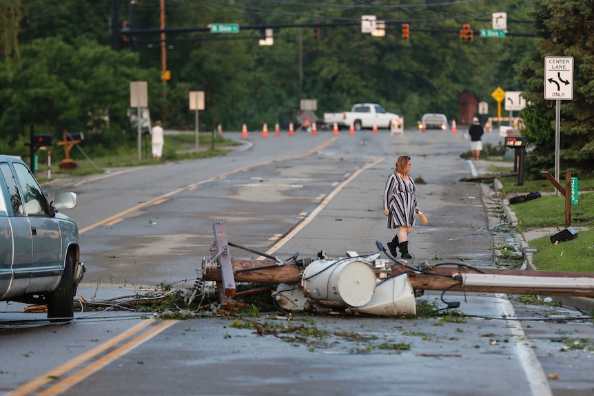 A powerline lies strew across a wet road as a woman walks past.