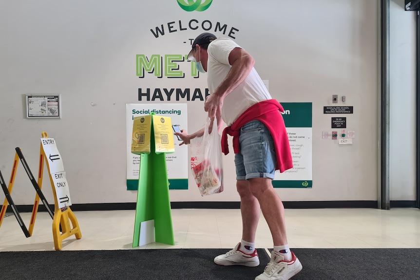 a man using his phone yo sign into a supermarket