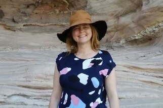 A woman smiling while wearing a hat