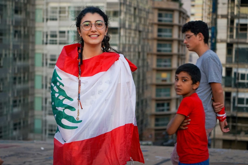 A young girl in pigtails wrapped in a Lebanese flag