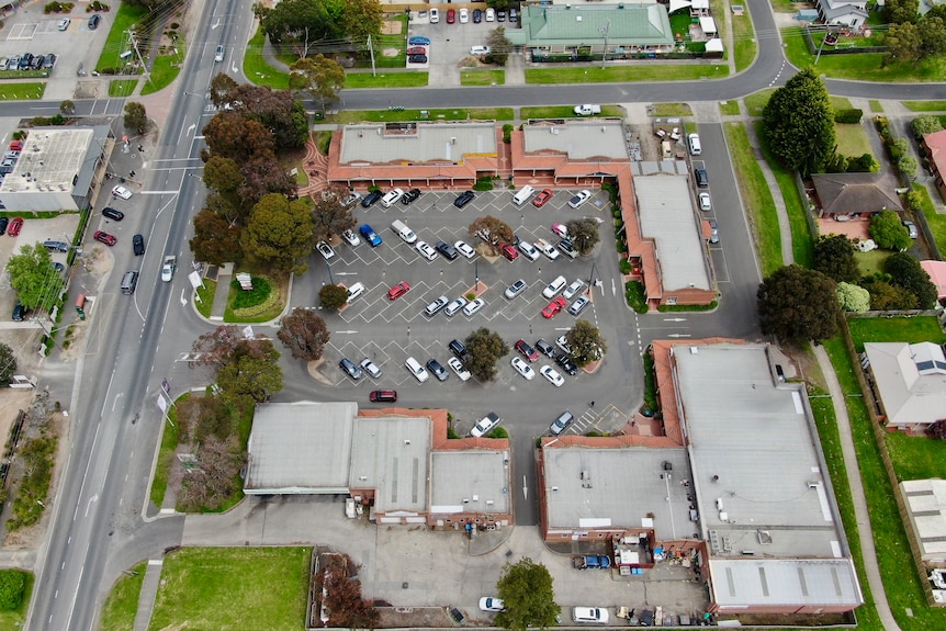 A drone image of cars in a carpark in a shopping square.