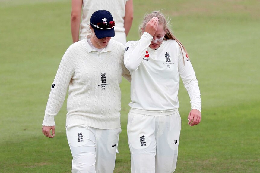 An England women's Test cricketer pats her teammate's back as she walks off the ground injured.