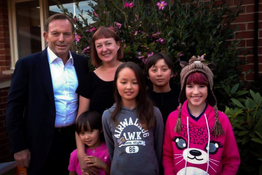 The former Prime Minister Tony Abbott is standing with Mary-Jane Liddicoat and her family.