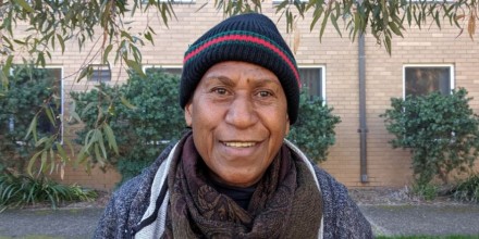 A woman wearing a beanie, jumper and scarf smiling