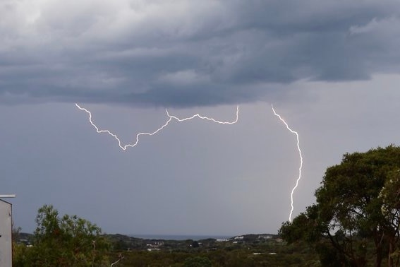 A lightning strike cutting through a grey sky.